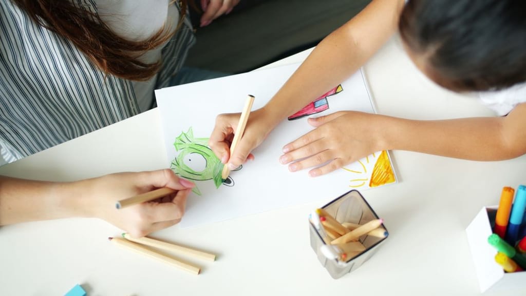 An adult and child drawing together during a learning activity at home, similar to ABA therapy exercises