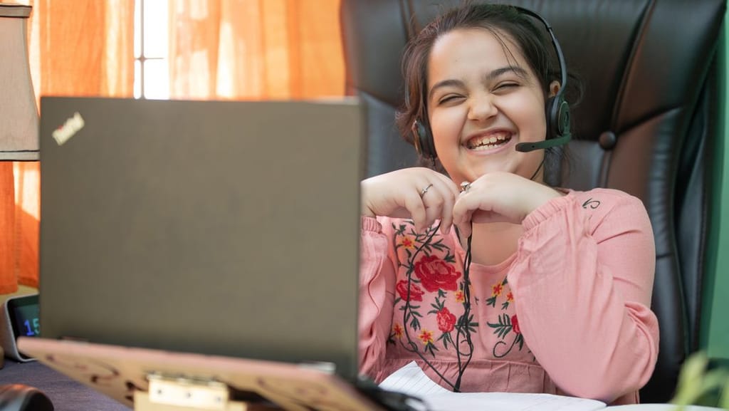 A smiling child wearing a headset during a virtual learning class at home