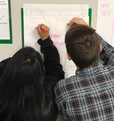 Cedars International Academy students working together at a classroom whiteboard in Austin.
