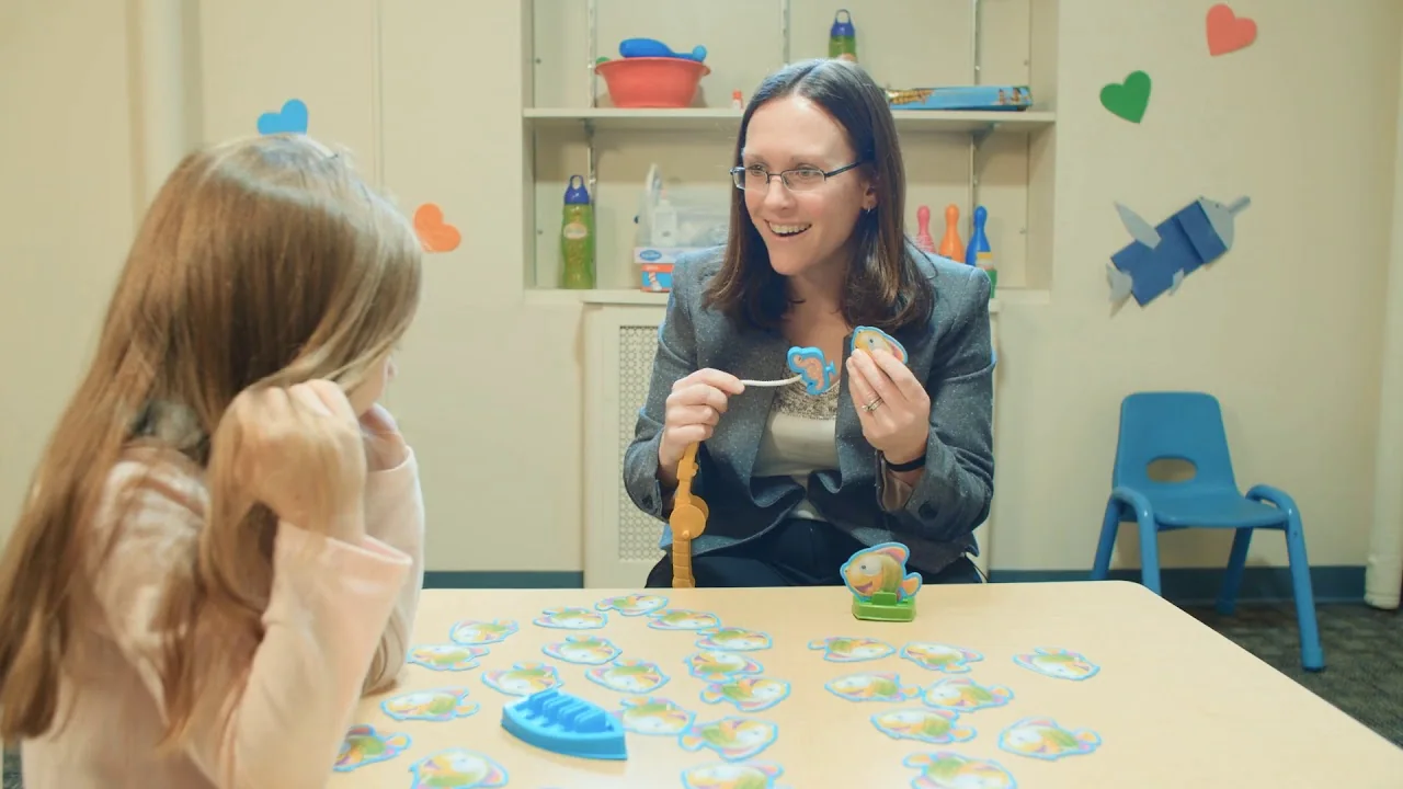 Therapist and child practicing communication at a table