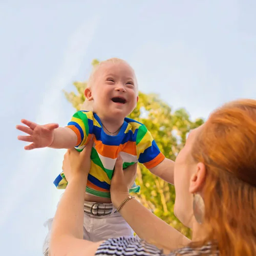 Adult lifting a smiling young child outdoors