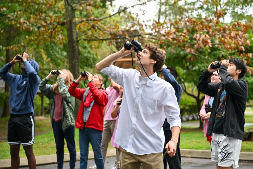 Asheville School students using binoculars during an outdoor lesson.