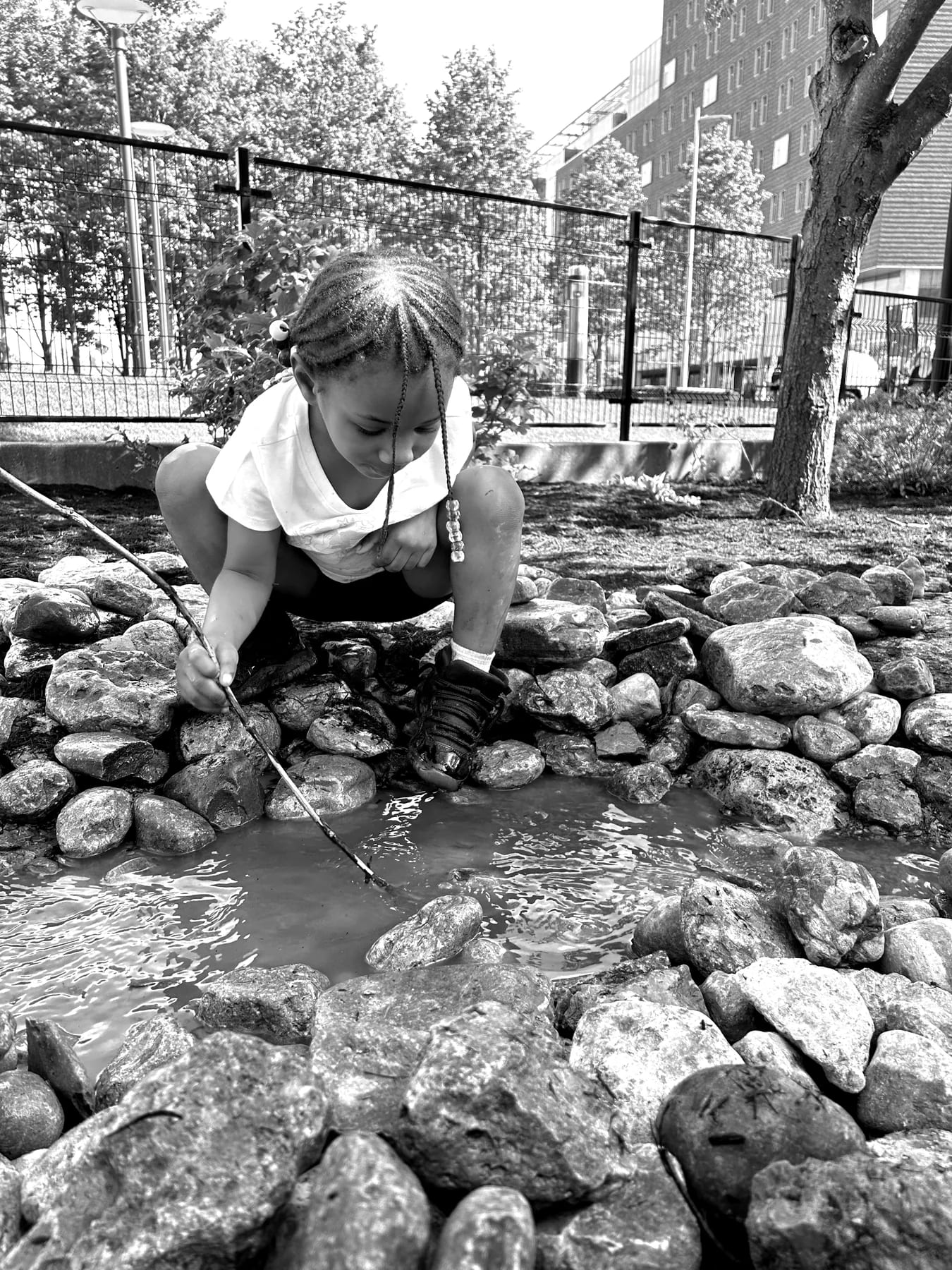 Young child investigating rocks and water outdoors at the Arlitt Center.