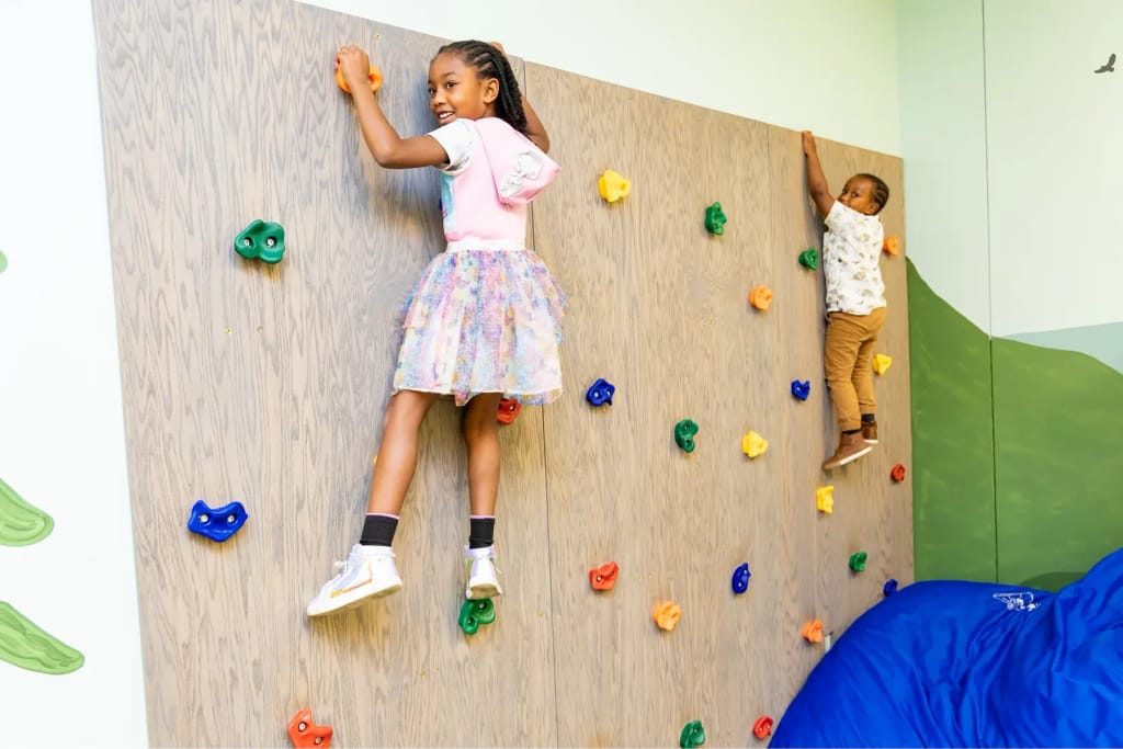 Children using a climbing wall at Woven Care Woodmen