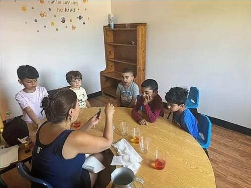 Children participating in a small-group activity with an adult at myTRIBE by The 7Q Foundation.