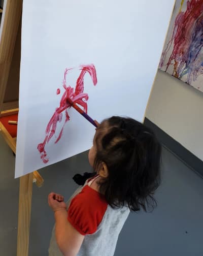 Child painting at an easel at Bilingual First Steps Education in Gresham