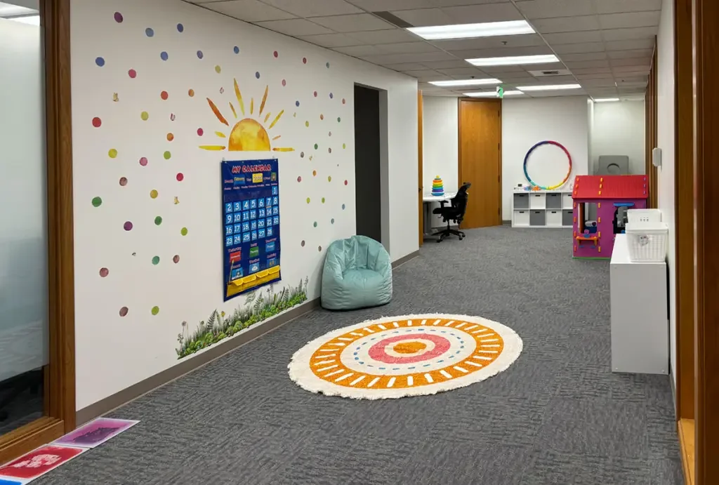 Indoor therapy space with colorful wall art and play equipment at All in ABA Federal Way.