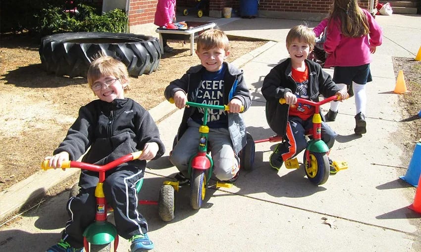 A Child's Garden Preschool children riding tricycles together outside.