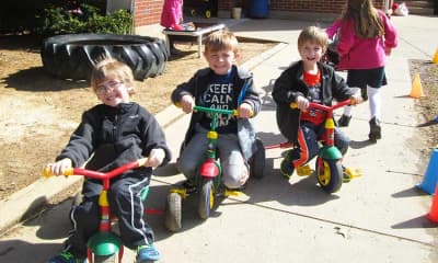 A Child's Garden Preschool children riding tricycles together outside.
