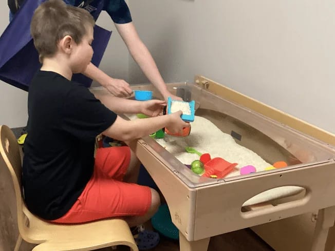 A child exploring a sensory play station at Merlin Day Academy