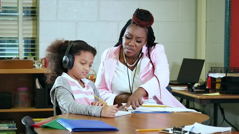 Adult supporting a student working at a desk