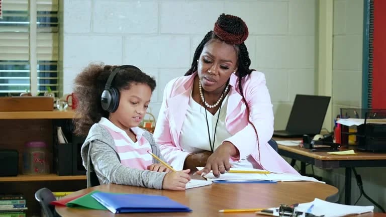 Adult supporting a student working at a desk
