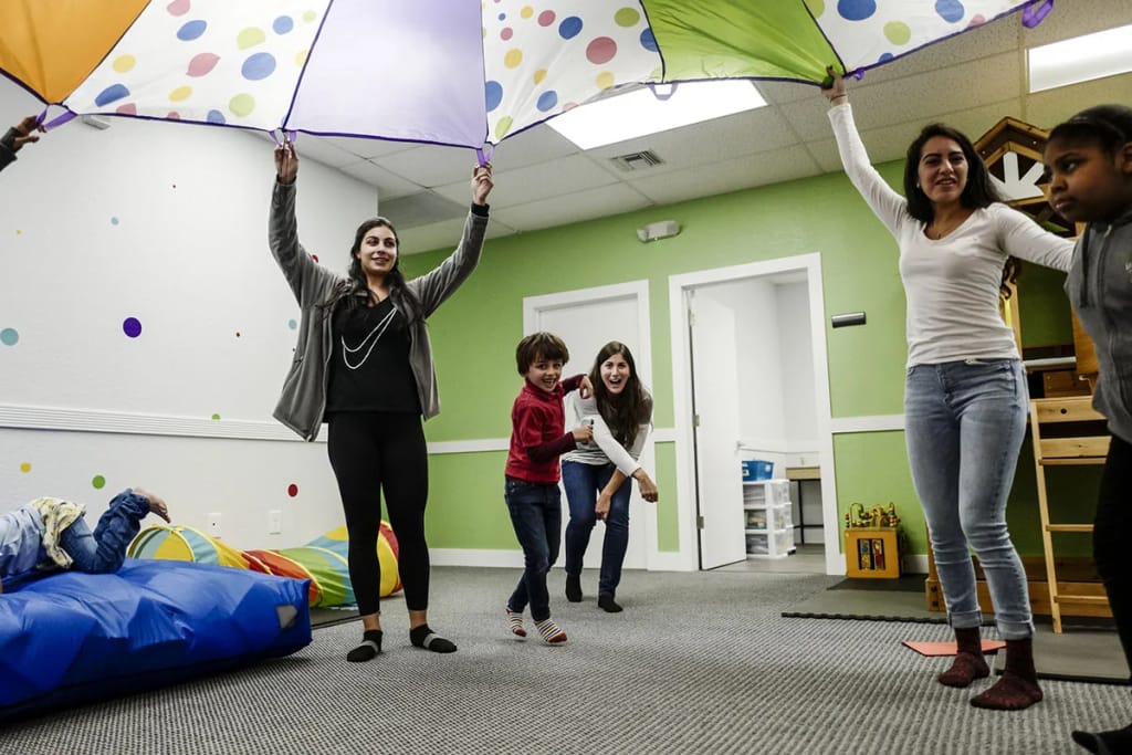 InBloom staff and children participating in an indoor expressive activity.