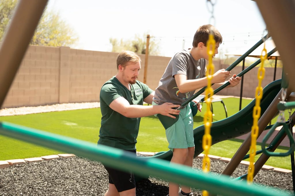 Arizona Autism staff member supporting a child during an outdoor activity.
