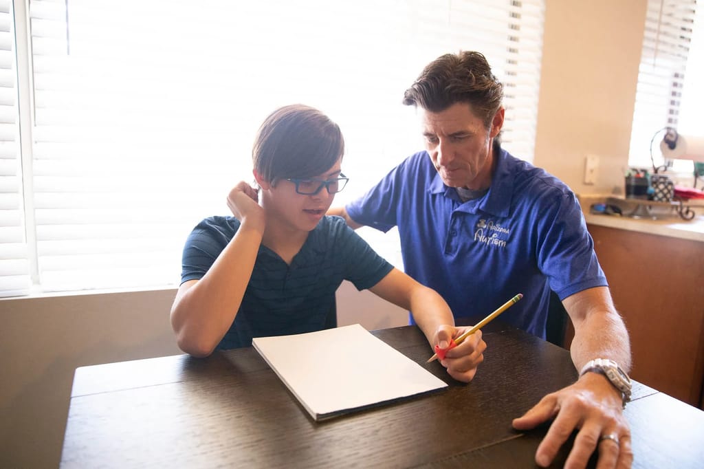 Arizona Autism staff member assisting a child with a learning activity indoors.