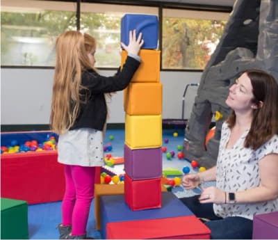 Child and therapist participating in a center-based activity at Early Autism Services.