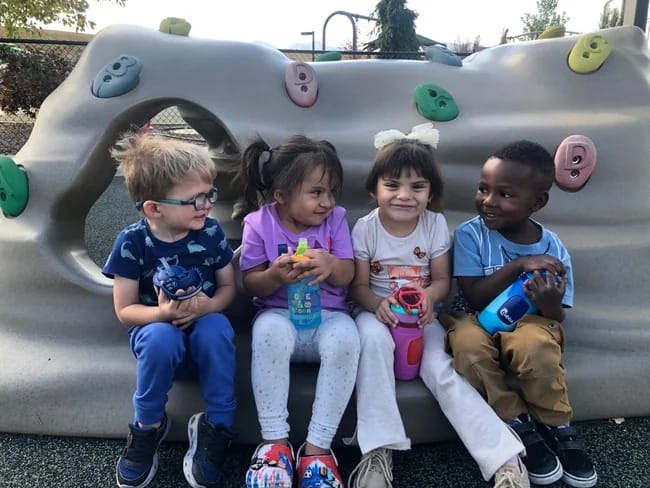 Young Rocky Mountain Deaf School students sitting together outside