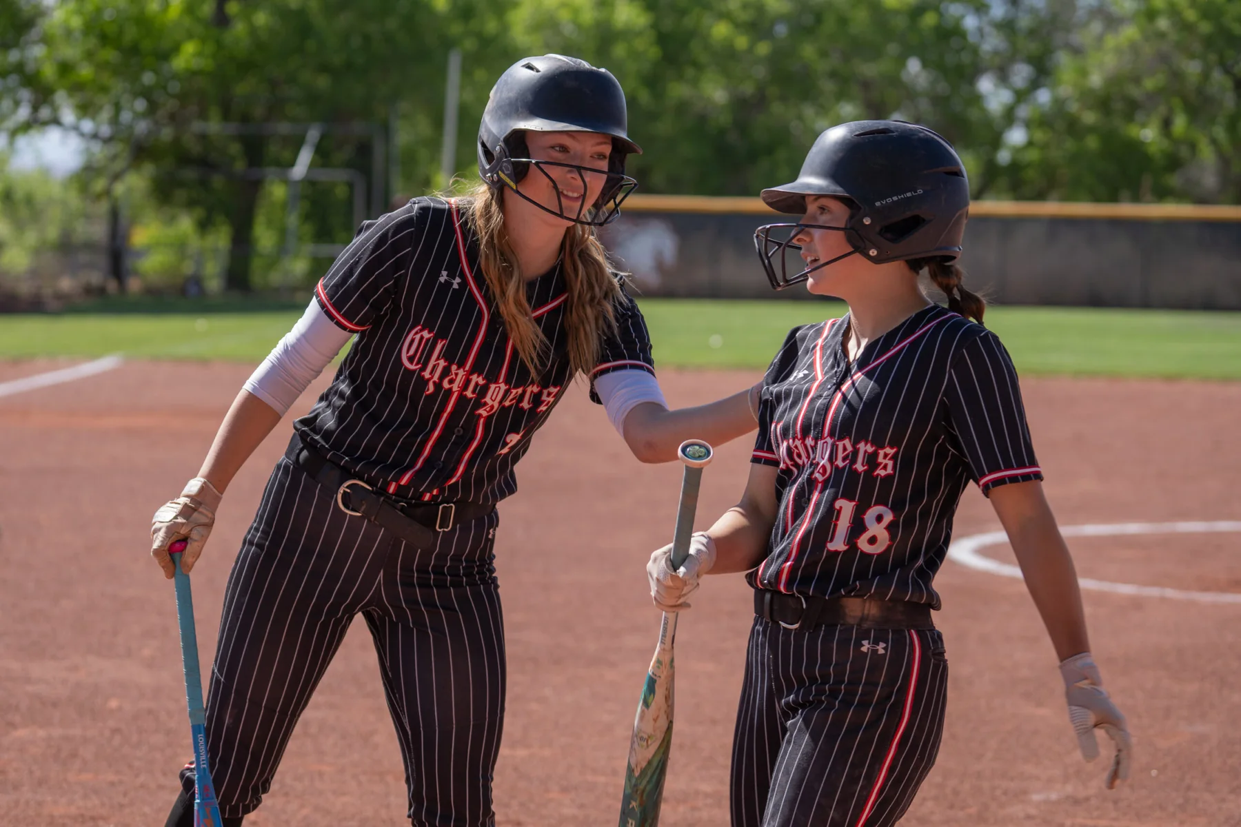 Two Albuquerque Academy softball players greeting each other on the school field.