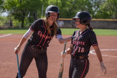 Two Albuquerque Academy softball players greeting each other on the school field.