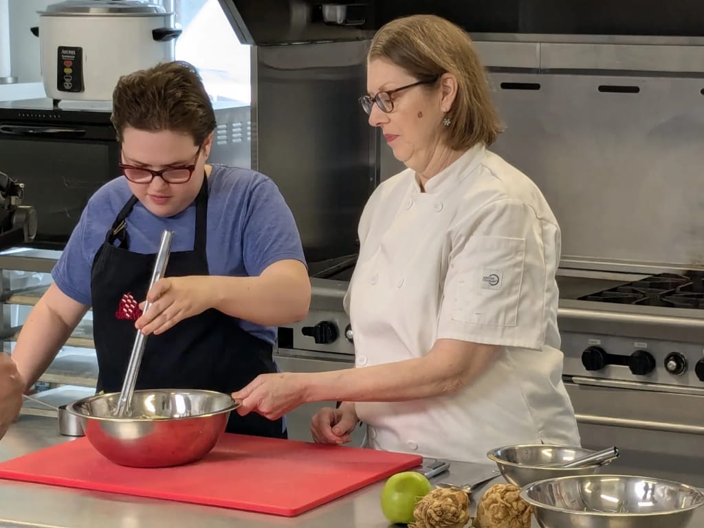 Participant and instructor working together during a cooking activity at Commonwealth Autism.