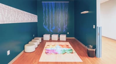 Indoor sensory activity room with floor seating and an art table at Action Behavior Centers.