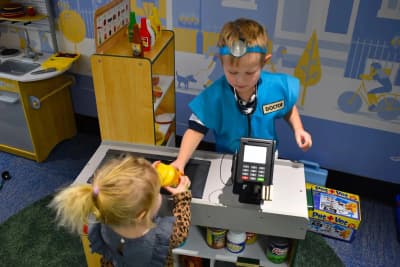 Child playing in a pretend store inside the Centennial center