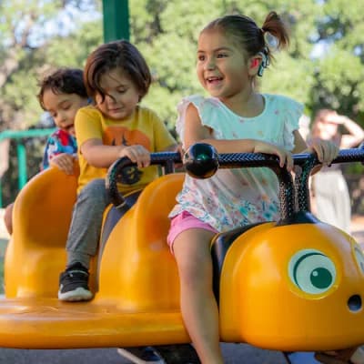 Sunshine Cottage students riding playground equipment