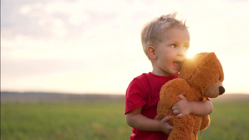 Young child holding a teddy bear outdoors