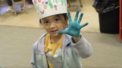 Discovery Parent-Child Preschool student showing a blue painted hand