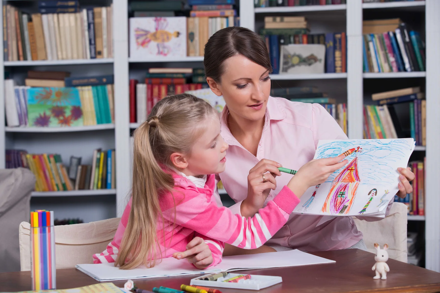 Adult helping a child with a drawing activity