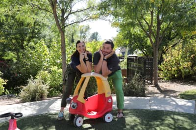 Elizabeth Academy student riding a toy car with two staff members outdoors.