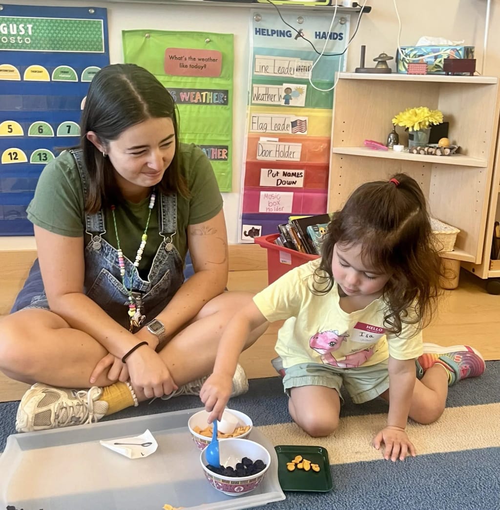 Elizabeth Academy teacher helping a young student with hands-on classroom materials.