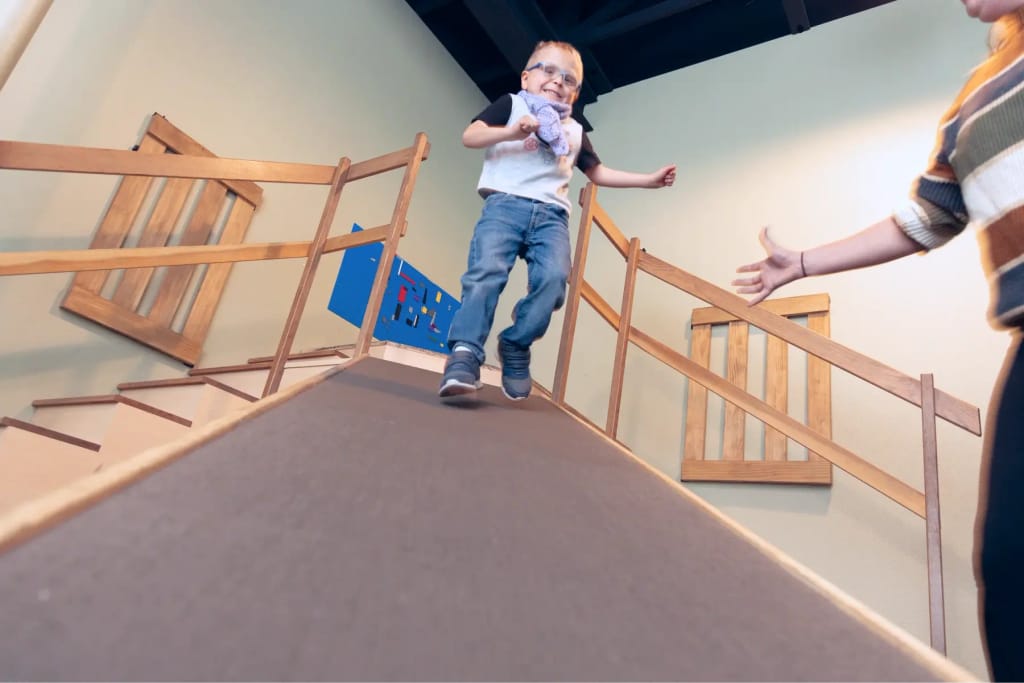 Child using a wooden ramp inside Woven Care Pueblo North