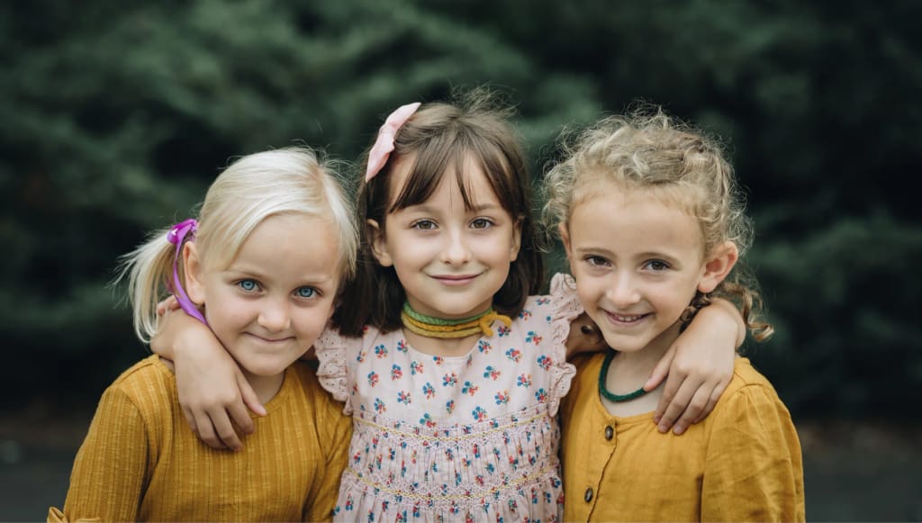 Three Asheville Waldorf School students standing together outdoors.