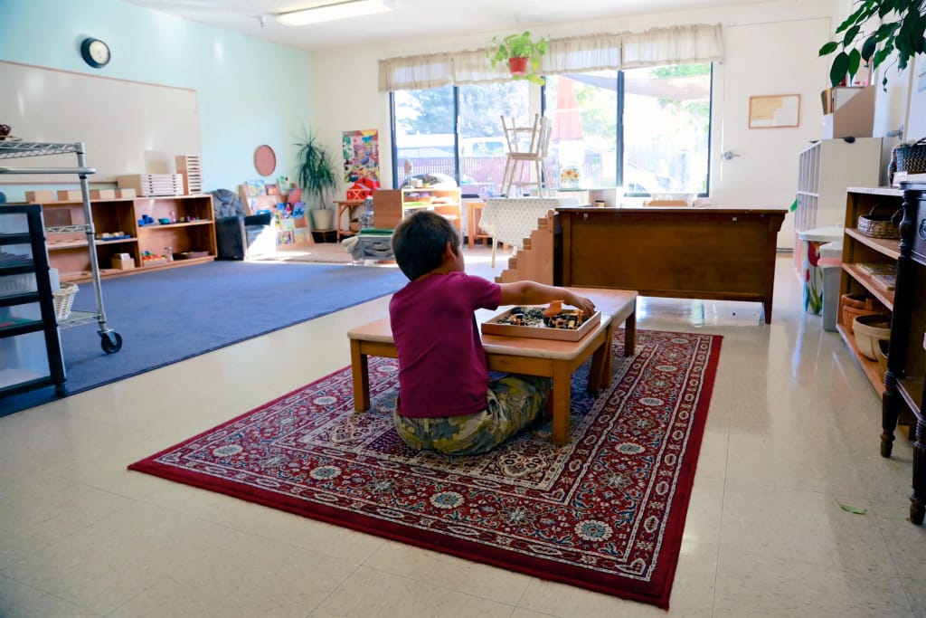 Montessori Children's School classroom with a child working at a learning table.