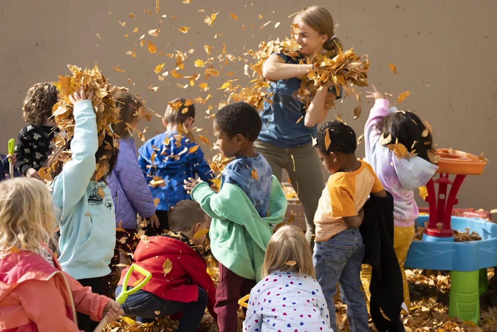 Rocky Mountain Preschool children playing together in autumn leaves