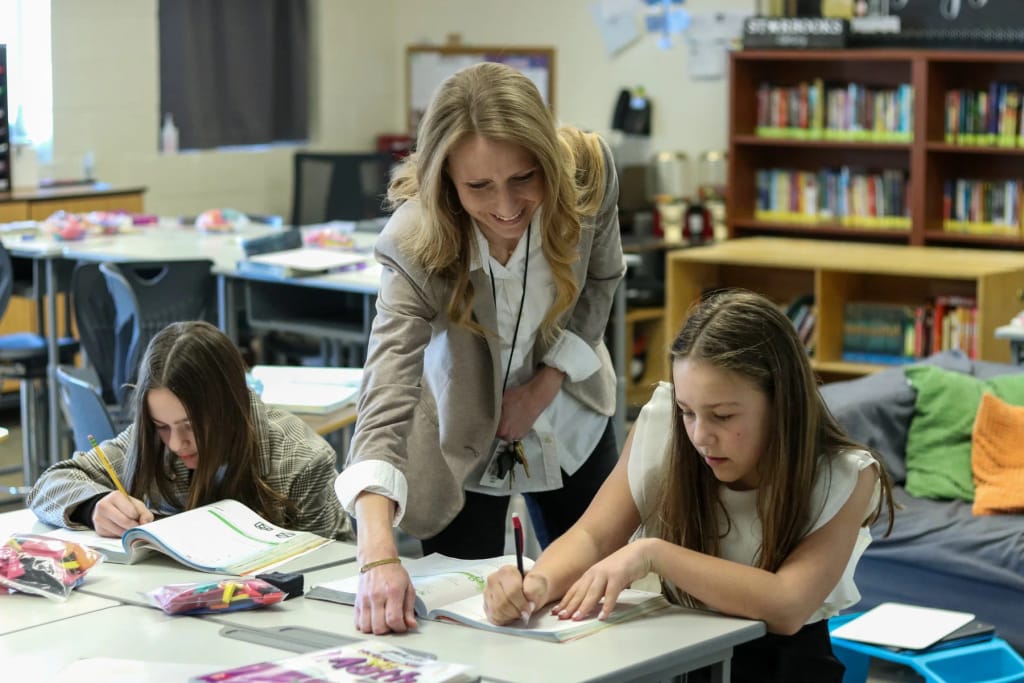 Intermountain Christian School teacher assisting students with work at a classroom table.