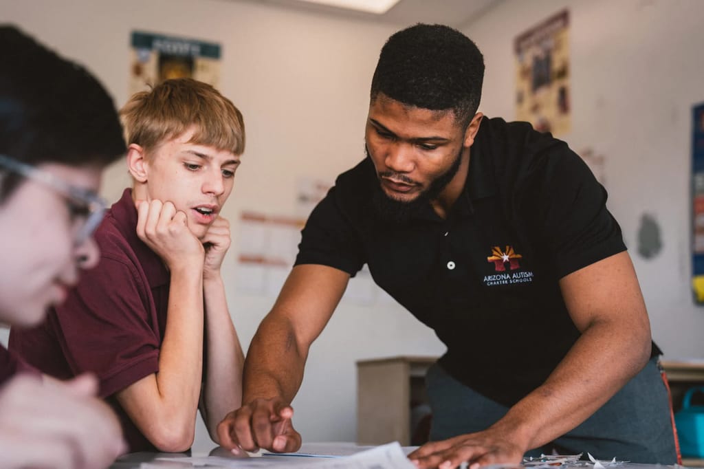 An Arizona Autism Charter School teacher supports a student in the classroom