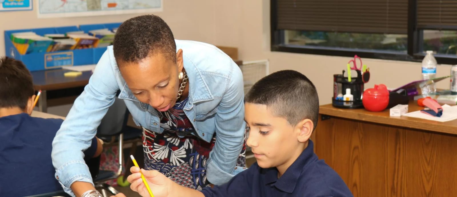 Pepin Academies teacher works with a student at a classroom table.