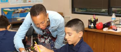 Pepin Academies teacher works with a student at a classroom table.