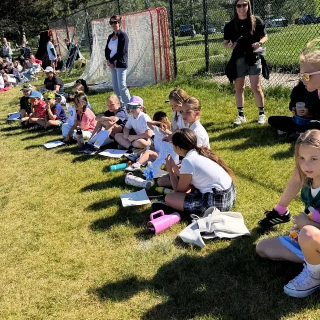 J.E. Cosgriff Memorial Catholic School students seated together on the grass.