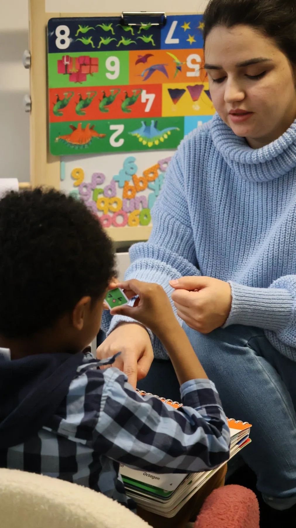 Therapist supporting a child during a learning activity at Autism Reimagined Center.