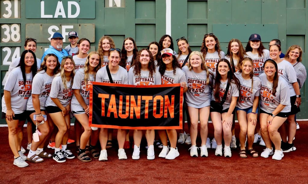 Taunton High School students and staff pose with a school banner.