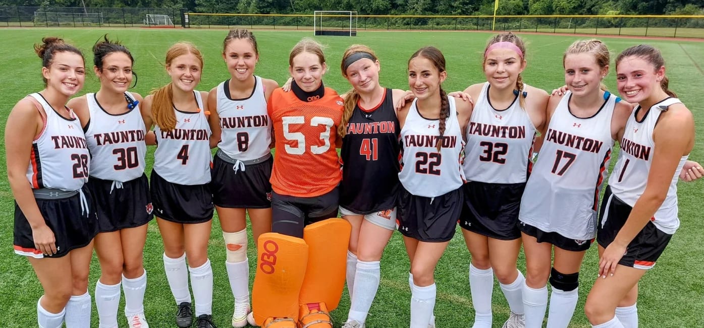 Taunton High School field hockey players pose together on the field.