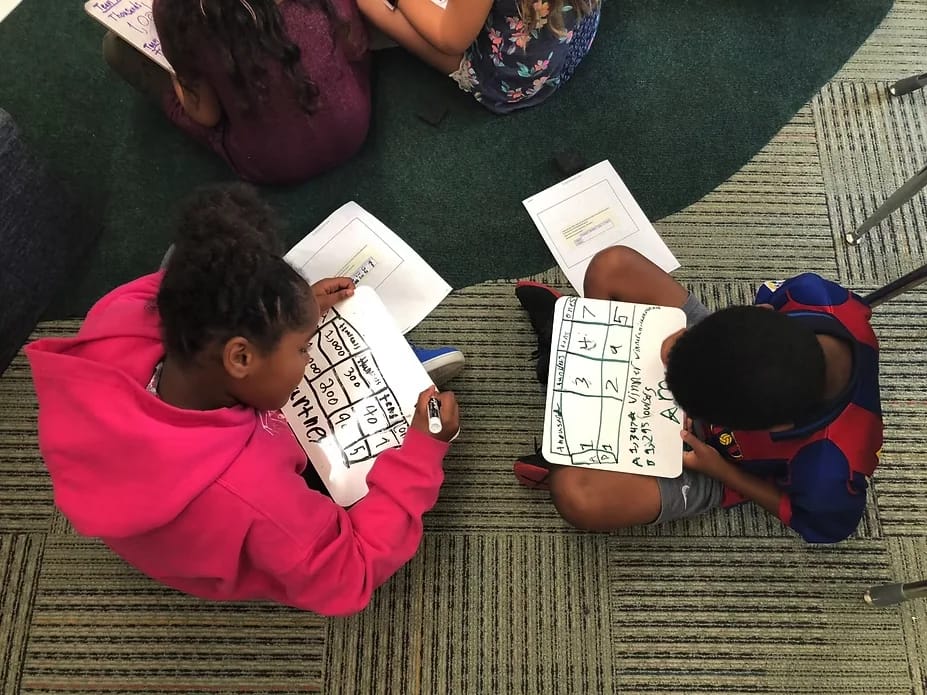 Grand Rapids Child Discovery Center students completing classroom work on the floor.