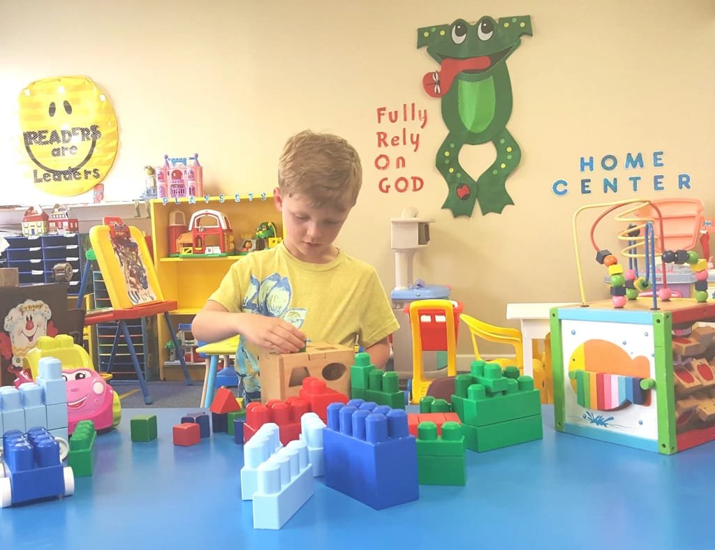 Child exploring colorful blocks in a PBC Preschool classroom.