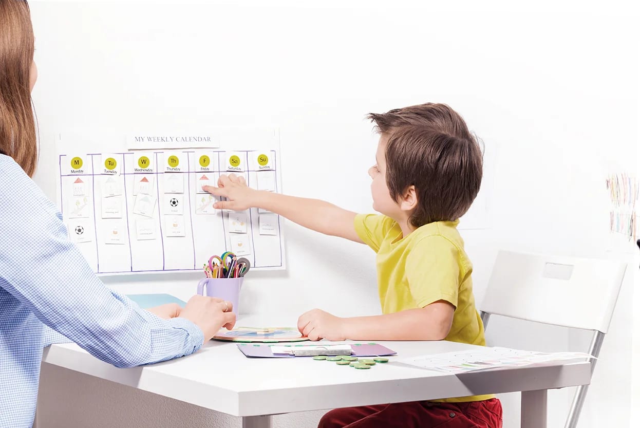 Adult and child using a visual activity schedule at a table