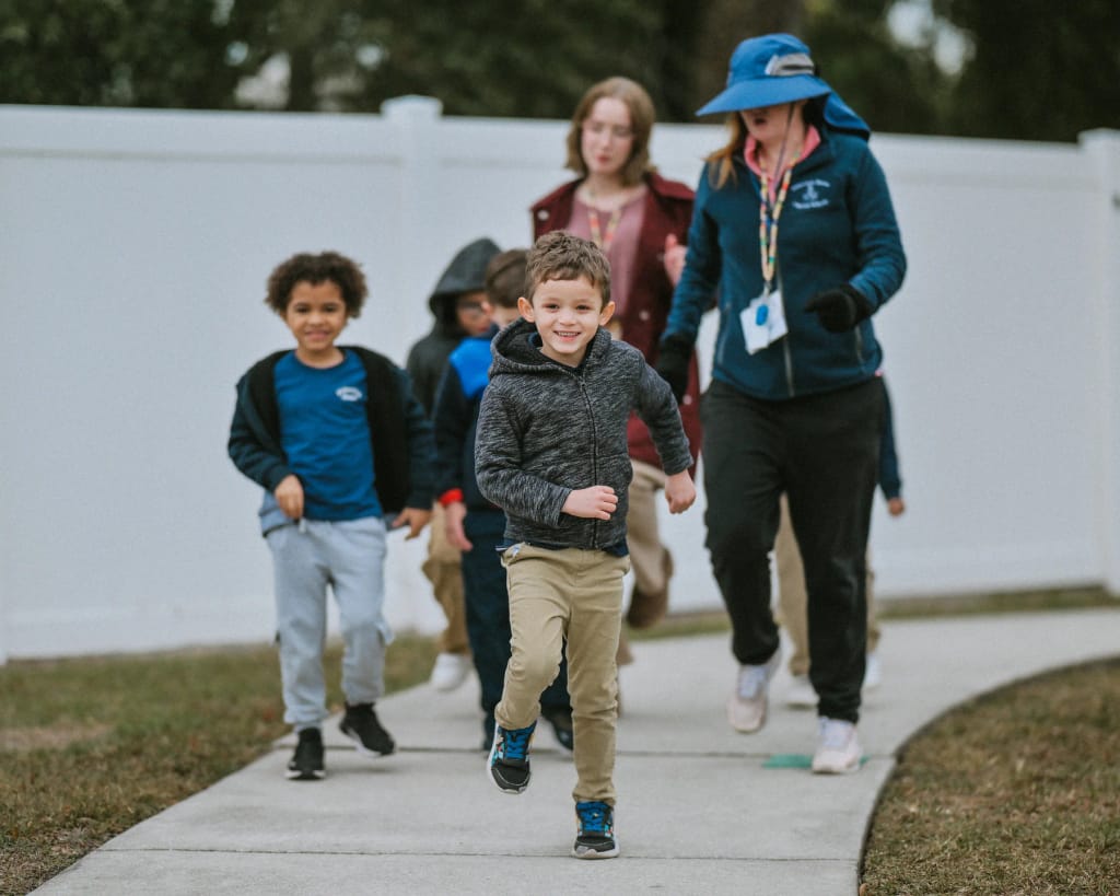 Princeton House Charter School students run outdoors with a teacher