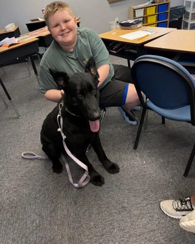 A Victory Autism Academy Phoenix student sits with a classroom therapy dog