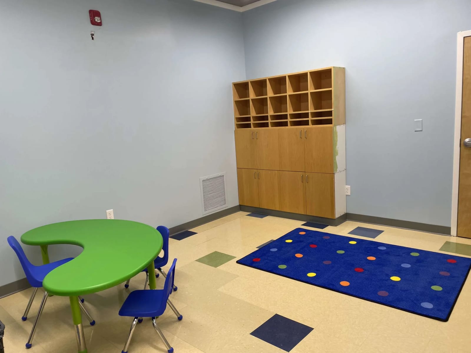 Indoor therapy room with child-sized tables and a colorful activity rug at ABI New England.
